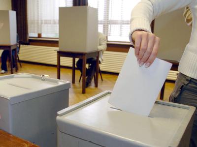 Eine Wählerin steckt bei einer Kommunalwahl ihre Stimmzettel in die Wahlurne. Stimmabgabe