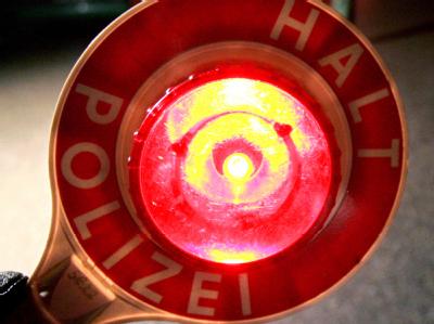 Mit einer roten Polizeikelle werden Fahrer zu einer Alkoholkontrolle gewunken. Polizeikelle