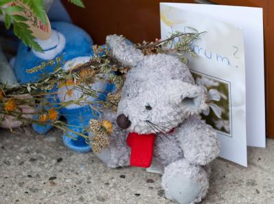 Kerzen, Blumen und Plüschtiere erinnern vor einem Hauseingang an ein getötetes Kleinkind. Gedenken