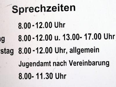 Ein Schild weist an der Außenwand einer Behörde auf die Öffnungszeiten des Jugendamts hin. (Archiv- und Symbolbild) Öffnungszeiten
