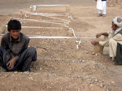 Afghanische Männer neben Gräbern mit den Opfern eines US-Angriffs in der Provinz Farah (Archivfoto) Trauer