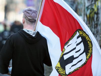 Ein Mitglied der rechtsextremen NPD mit einer Fahne der Partei. Foto: Stephan Scheuer NPD-Kundgebung
