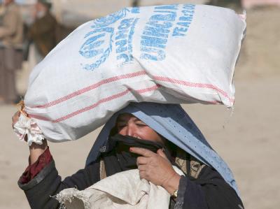 Eine Afghanin trägt einen Sack mit Lebensmitteln des UN-Flüchtlingskommissariats UNHCR. Hilfe