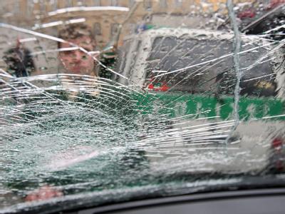 Ein Polizist betrachtet in Leipzig einen durch Hooligans beschädigten Einsatzwagen. (Archivfoto) Zerstörte Frontscheibe