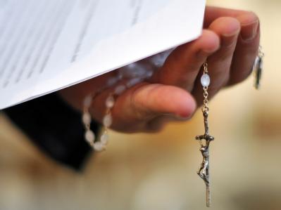 Ein Priester hält einen Rosenkranz und eine bischöfliche Erklärung zu den Missbrauchsfällen durch Jesuiten-Pater in der Hand. (Archivbild) Rosenkranz