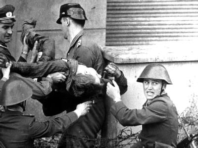 Grenzposten tragen 1962 in Berlin den leblosen Körper von Peter Fechter weg. Der angeschossene 18-Jährige hatte vor seinem Tod eine gute Stunde um Hilfe gerufen, ohne dass die Grenzer ihm halfen. Tod an der Berliner Mauer