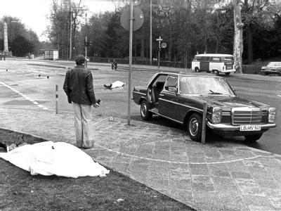 April 1977: Der Tatort mit der zugedeckten Leichen von Siegfried Buback (vorne links). Mit ihm starben sein Fahrer (43) und der 30-jährige Leiter der Fahrbereitschaft. Tatort