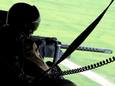 Ein Soldat überwacht auf dem Flug nach Kundus mit einem schweren Maschinengewehr die Umgebung. Schussbereit