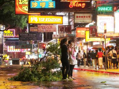 Fußgänger in einer Straße von Hongkong neben einem vom Sturm umgerissenen Baum. Taifun über Hongkong