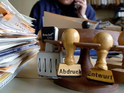 Bereits elf Prozent aller Fehltage gehen auf das Konto der steigenden psychischen Belastung in der modernen Arbeitswelt. (Symbolbild) Aktenstapel und Stempel