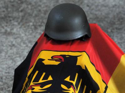 Ein Stahlhelm liegt auf dem mit der deutschen Flagge bedeckten Sarg eines Bundeswehr-Soldaten, der im Juni 2009 in Afghanistan ums Leben kam. Trauerfeier für getötete Bundewehr-Soldaten