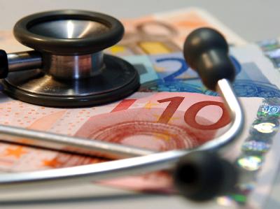 Stethoskop auf Geldscheinen. Mehrere Krankenkassen werden wohl Zusatzbeiträge erheben. (Symbolbild) Stethoskop