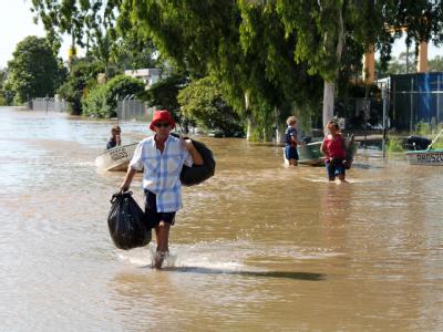 Einwohner der australischen Stadt Rockhampton waten durch eine überflutete Straße. Rockhampton