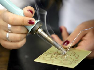 Eine Frau lötet an einer Platine: Gleicher Lohn für gleiche Arbeit - Das ist immer noch keine Selbstverständlichkeit. Frauentag