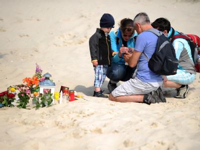 Eine Familie zündet auf Amrum vor dem Klettergerüst «Piratenschiff» eine Kerze an. Foto: Daniel Reinhardt Gedenken an toten Sebastian auf Amrum