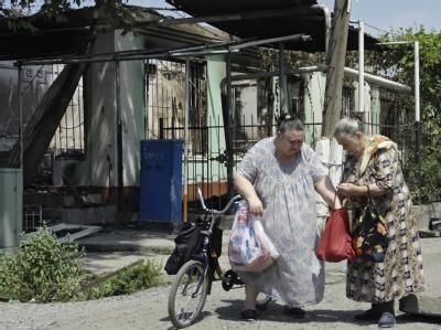 Zwei Frauen stehen vor einem Haus, das während der Unruhen abgebrannt ist. Zehntausende Menschen sind auf der Flucht. Leben im Chaos