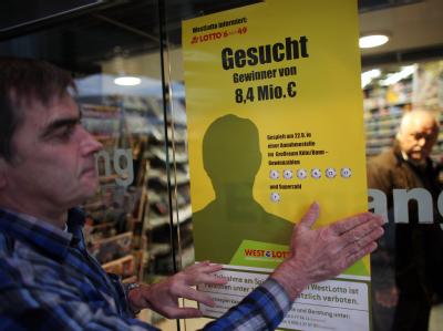 Der Besitzer eines Lotto-Geschäftes in Köln mit dem «Fahndungsplakat». Lottogewinner wird gesucht