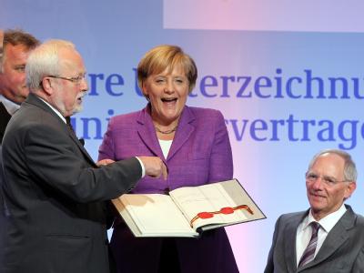 Lachend hält Bundeskanzlerin Angela Merkel (CDU) das historische Schriftstück in den Händen. V.l.: Der ehemalige DDR-Staatssekretär Günther Krause, Lothar de Maiziere, Bundeskanzlerin Merkel und Bundesfinanzminister Schäuble, ehemals Bundesinnenminister. Festveranstaltung 20 Jahre Einheitsvertrag