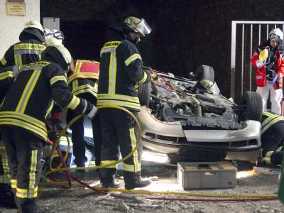 Feuerwehrleute untersuchen das herabgestürzte Auto. Auto stürzt vom Parkhaus