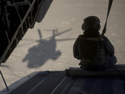 Ein Bundeswehrsoldat, der auf der Ladeklappe eines Bundeswehr-Hubschraubers sitzt, beobachtet während eines Fluges in Afghanistan die Landschaft. Bundeswehr in Afghanistan