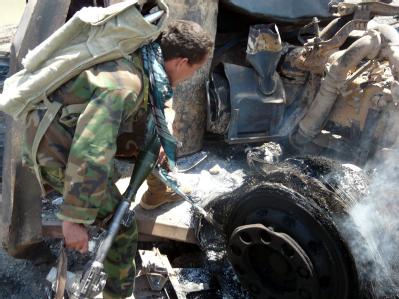 Ein afghanischer Soldat inspiziert einen der ausgebrannten Tanklastzüge. Ausgebrannter Tanklaster