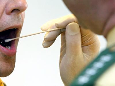 Ein Polizeihauptkommissar nimmt eine Speichelprobe von einem Mann. (gestellte Szene, Archivbild) DNA-Massentest