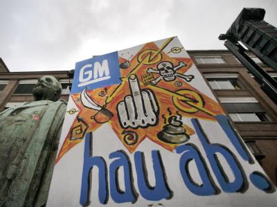 Drastisch: Ein Plakat mit wütendem Protest gegen GM steht an der Adam-Opel-Statue vor dem Werk in Rüsselsheim. Protest in Rüsselsheim