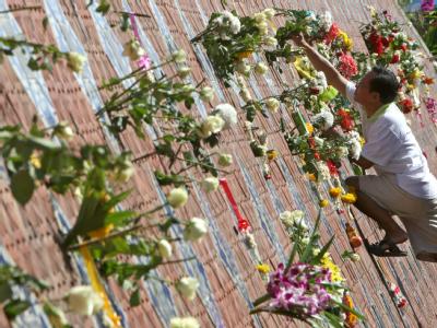 Ein Thailänder bringt Blumen an der Mauer der Erinnerung in Süd-Thailand an. Mauer der Erinnerung