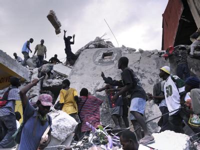 Haitianer versuchen, Waren zu ergattern, die vom Dach eines geplünderte Ladens in Port-au-Prince geworfen werden. Plünderungen in Port-au-Prince