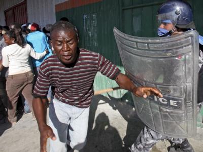 Ein UN-Polizist in Kampfmontur stellt sich einer Gruppe Haitianer in den Weg. Unruhen in Port-au-Prince