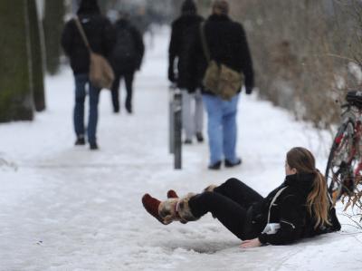 Eine Passantin liegt in Hamburg auf dem Boden, nachdem sie auf dem rutschigen Boden ausgerutscht ist. Der Frost hat am Donnerstagmorgen zu vielen Einsätzen von Polizei und Feuerwehr auf Hamburgs Straßen geführt. Glatteis in Hamburg