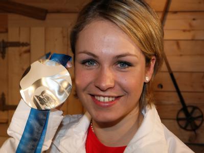 Stolz zeigt Biathletin Magdalena Neuner ihre erste olympische Medaille. Strahlend