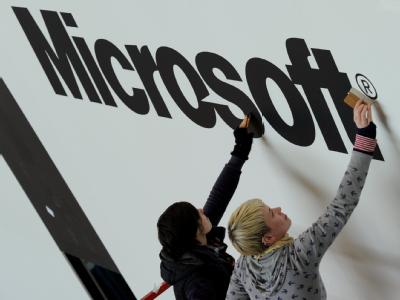 Zwei Mitarbeiterinnen einer Messeaufbau-Firma kleben auf dem CeBIT Stand von Microsoft einen Firmenschriftzug auf. CeBIT 2010 - Aufbau