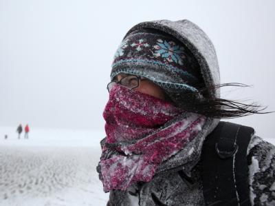 Mit einem Schal schützt sich bei Schneetreiben eine Spaziergängerin am Strand von in St. Peter-Ording gegen die Kälte. Schnee in St. Peter-Ording