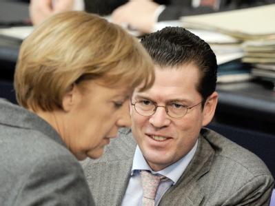 Bundeskanzlerin Merkel und Verteidigungsminister zu Guttenberg (CSU) unterhalten sich im Bundestag. Guttenberg steht wegen der Kundus-Affäre verschärft in der Kritik. Merkel und Guttenberg