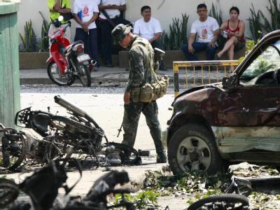 Ein Soldat steht zwischen beschädigten Fahrzeugen: Im Süden der Philippinen sind bei einer Serie von Bombenanschlägen mehrere Menschen ums Leben gekommen. Bombenserie auf den Philippinen