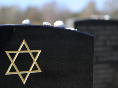 Steine liegen zum Gedenken an Verstorbene auf Grabsteinen auf dem Gelände der Gedenkstätte Bergen-Belsen. Bergen-Belsen