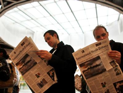 Ausländische Fluggäste lesen in einer Warteschlange im Terminal des Flughafens Düsseldorf die Berichterstattung über die Aschewolke. Flughafen Düsseldorf gesperrt