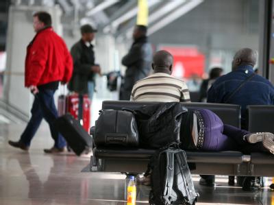 Passagiere schlafen im Hamburger Flughafen in der Wartezone auf Sitzbänken. Warten