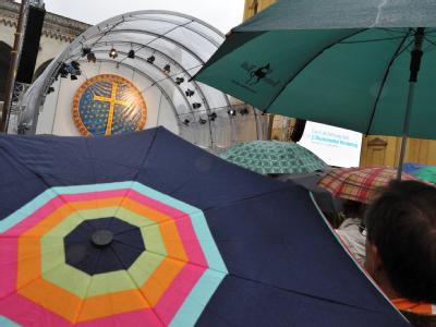 Gläubige verfolgen mit Regenschirmen die zentrale Ökumenische Feier zum 2. Ökumenischen Kirchentag. Bunte Schirme