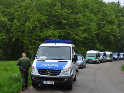 Polizeieinsatzfahrzeuge stehen bei Großkuchen an einem Wald. Fahndung