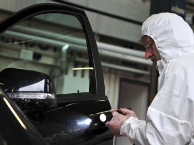 Ein Kriminaltechniker untersucht die Fahrertür des gefundenen Autos. Spurensuche
