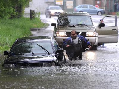 Ein Mann versucht sein Auto auf einer überfluteten Straße in Tschechien zu retten. Hochwasser in Tschechien