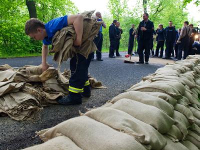 Einsatzkräfte der Feuerwehr errichten an einer Straße in Frankfurt (Oder) vorsorglich einen Wall aus Sandsäcken. Brandenburg erwartet Hochwasser
