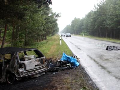 Ein verunglückter Pkw und ein abgedeckter Leichnam liegen auf der Bundesstraße bei Dolle in Sachsen-Anhalt. Unfall mit Leiche im Kofferraum