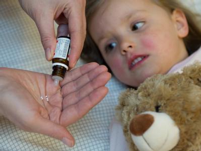 Eine Mutter gibt ihrer erkälteten Tochter ein homöopathisches Mittel. In der Politik ist ein hitziger Streit über Homöopathie auf Kassenkosten entbrannt. Homöopathie