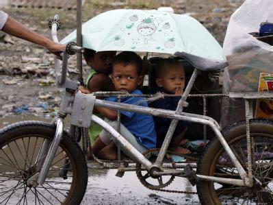 Eine Frau bringt ihre Kinder und ein paar Habseligkeiten in Sicherheit. nachdem ein Taifun ihr Haus zerstört hat. Taifun auf den Philippinen