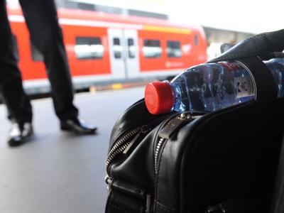Mit einer Wasserflasche im Reisegepäck steht ein Zuggast auf dem Hauptbahnhof in Hannover. Wasserflasche als Reisegepäck in der Bahn