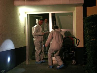 Polizisten untersuchen Spuren an einem Hauseingang. Spurensuche