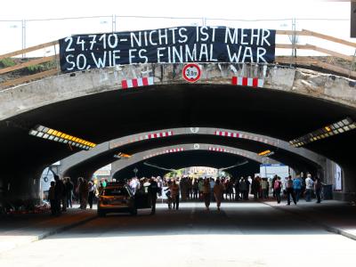 Ein großes Spruchband hängt am Zaun über dem Unglückstunnel in Duisburg. Unglücksort